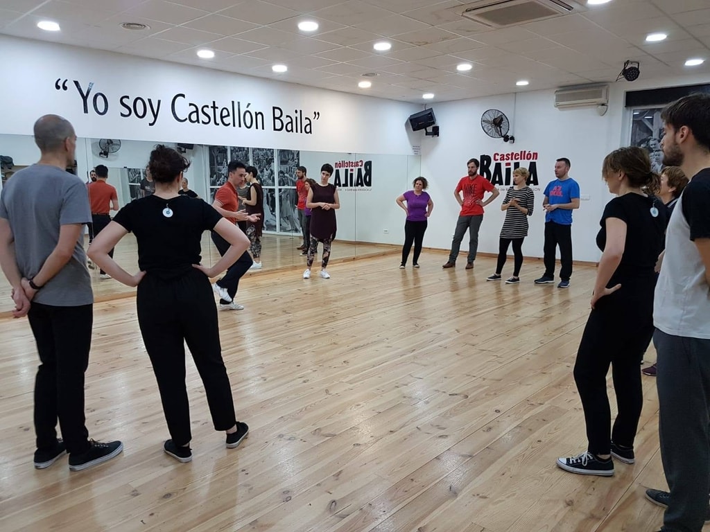 Swing dance students standing in a circle during a class at Castellon Baila dance studio with Kibble teaching the class